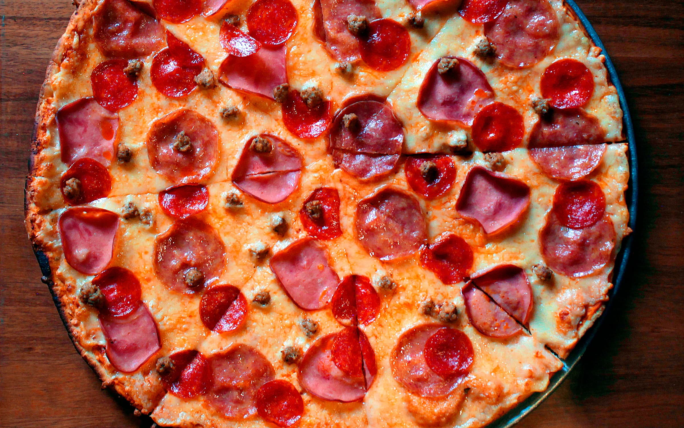 Salami-Pizza auf einem dunklen Holztisch