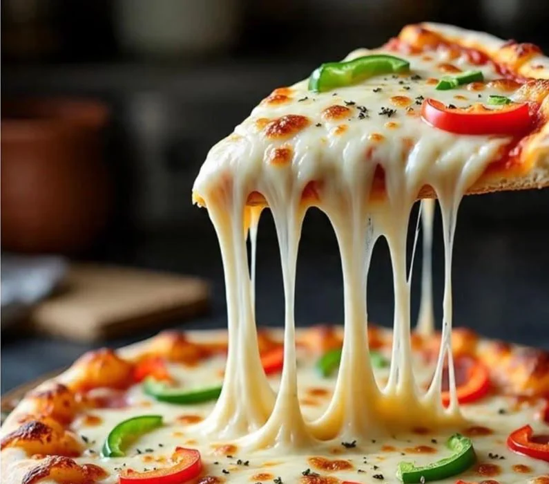 Pizzastück mit langen Käsefäden über einer Gemüsepizza