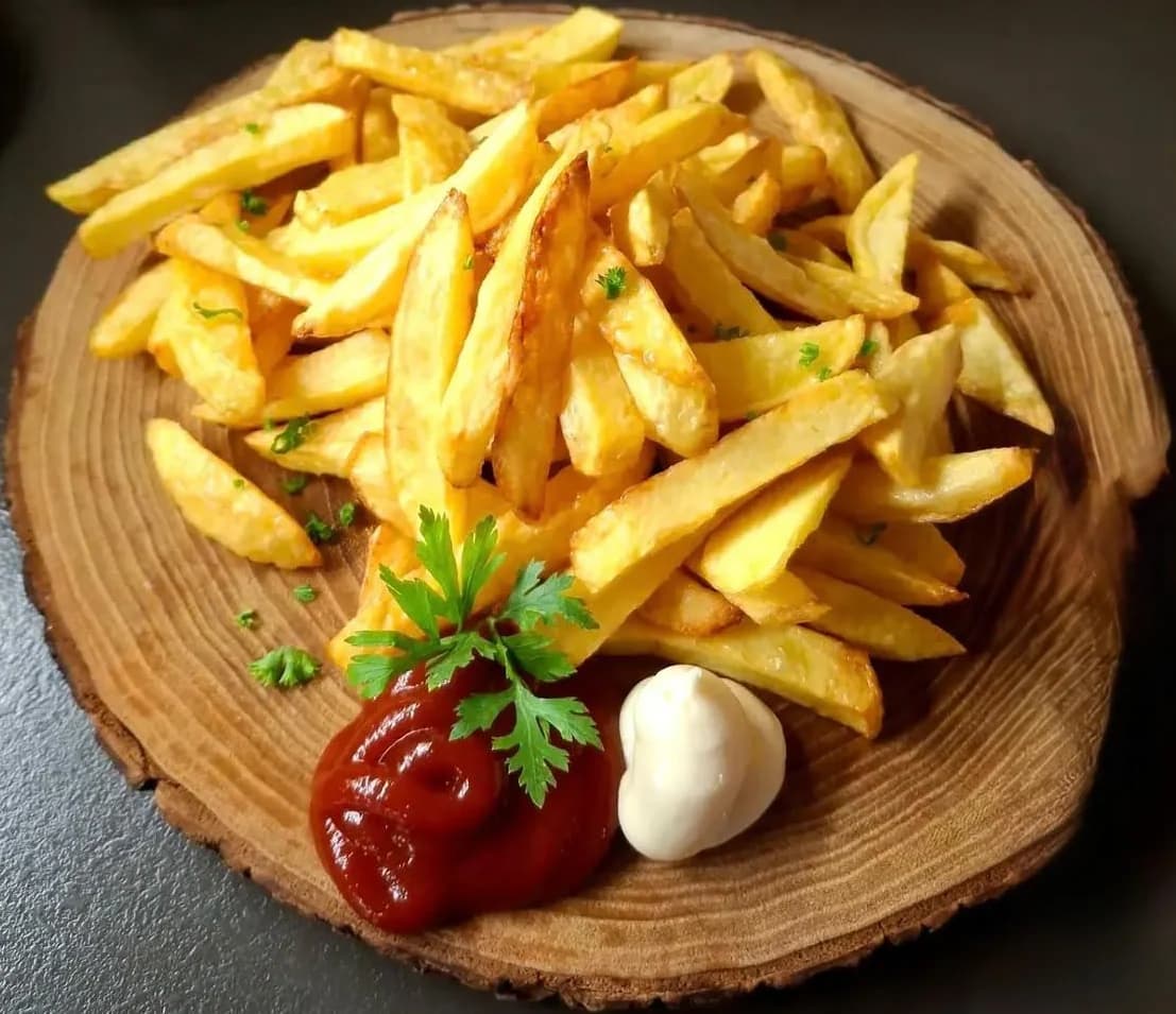Pommes auf einem Holzbrett mit Ketchup und Mayo