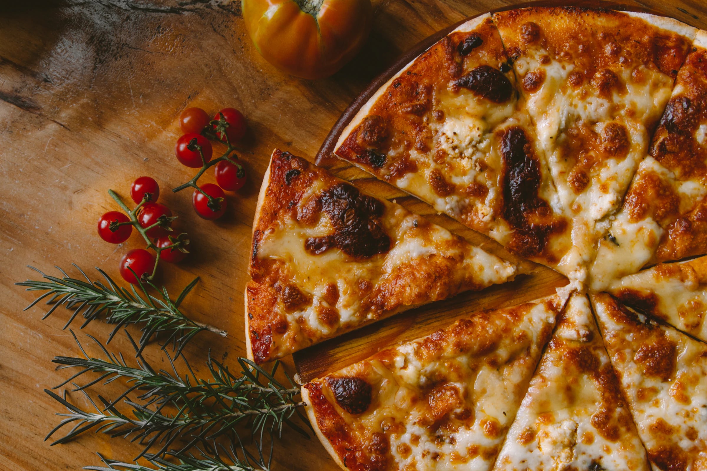 Frisch gebackene Pizza mit Kirschtomaten auf einem Holzbrett