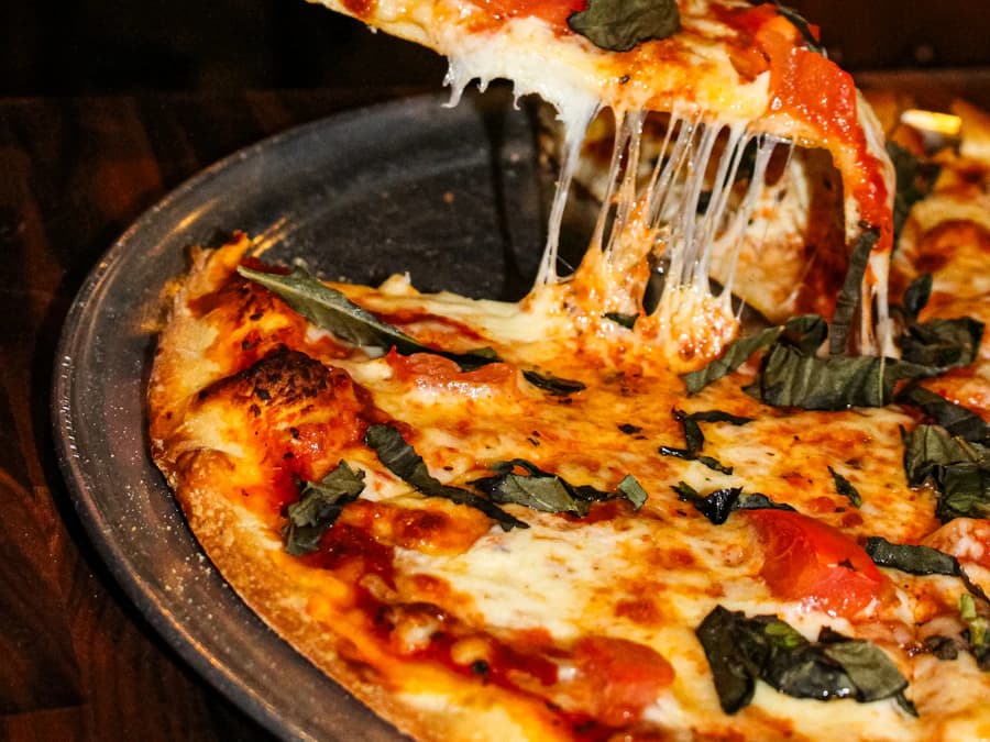 Pizzastück mit langen Käsefäden wird angehoben
